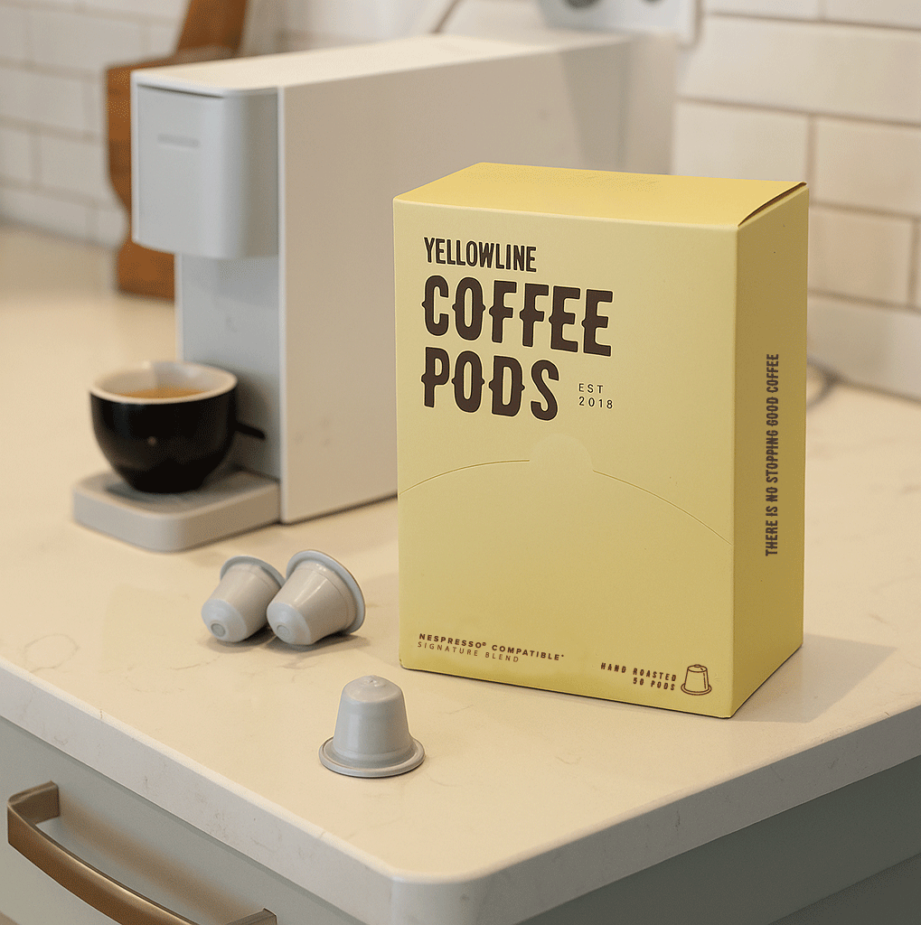 Yellowline Coffee Pods packaging on a kitchen counter with coffee pods and an espresso machine.