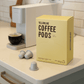 Yellowline Coffee Pods packaging on a kitchen counter with coffee pods and an espresso machine.